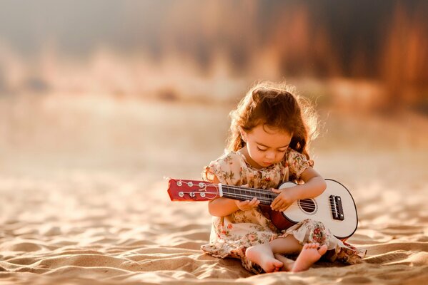 Una ragazza sulla sabbia con una chitarra suona melodie dal cuore