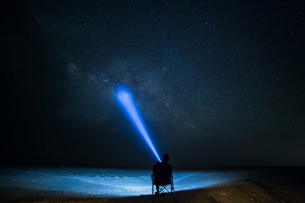 Человек светит фонарем на небо звёздное