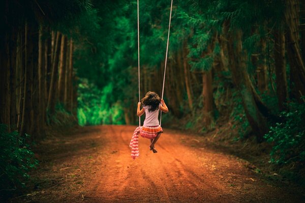 Columpio en el bosque con una chica montando