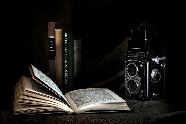 Открытая книга на фоне фотоаппарата и книг