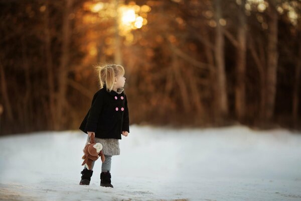 Chica con un juguete en un camino nevado