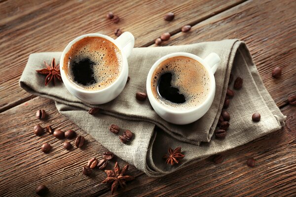 2 tazas de café en una servilleta alrededor de los granos de café