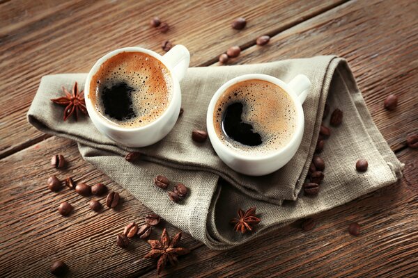 2 tasses de café sur une serviette autour des grains de café