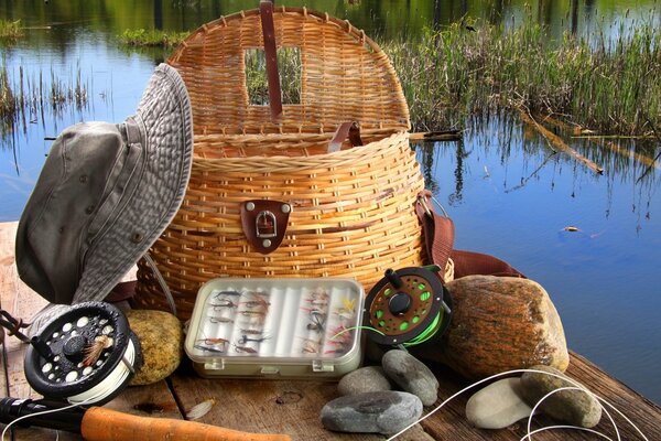 Matériel de pêche sur le pont. Chapeau. Étang. Panier en osier