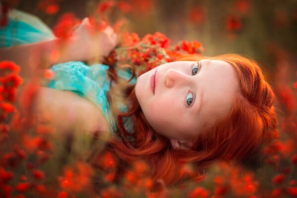 A red-haired girl in a meadow with flowers