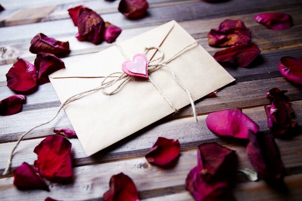 Enveloppe se trouve sur une table entourée de pétales de rose