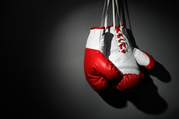 Красно белые боксерские перчатки висят на черной стене