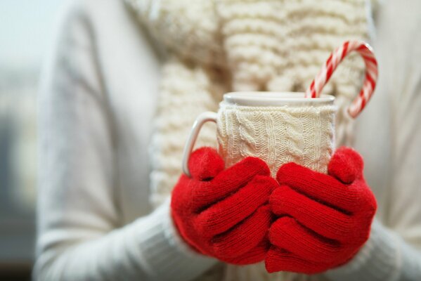 Manos con guantes rojos sosteniendo un vaso