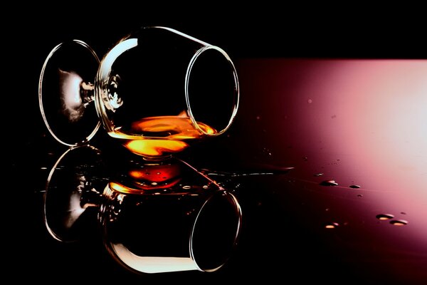 Gouttes de cognac sur verre de verre et de l alcool comme arrière-plan