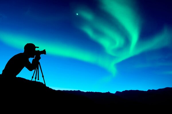 Silhouette of a photographer taking pictures of the Northern lights at night