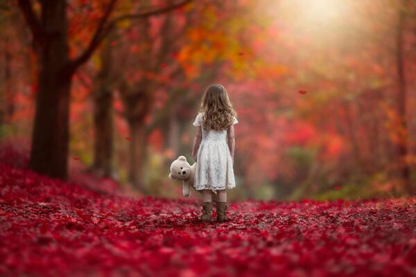 Chica con un juguete en el fondo del otoño dorado