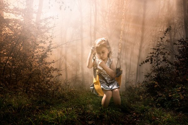 Petite fille sur une balançoire dans la forêt