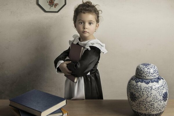 A little girl in a school uniform stands with a book in her hands