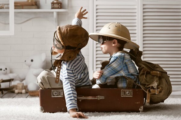 Boys play pilots sitting in a suitcase