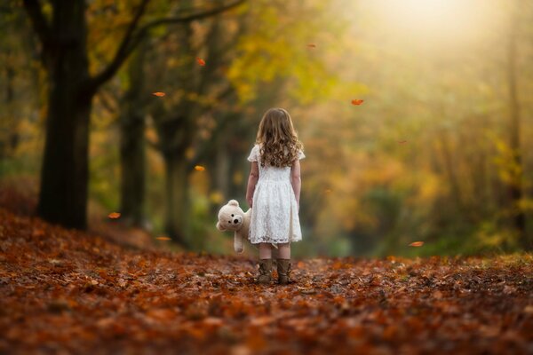 Fille avec jouet ours en peluche sur les feuilles d automne