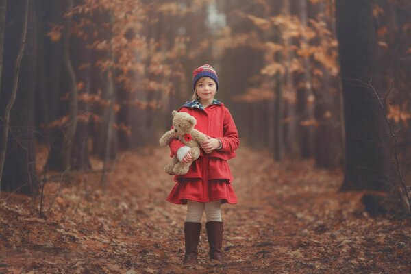 A girl in autumn in the forest with a teddy bear toy