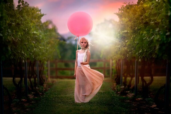 Chica con una bola rosa en la naturaleza