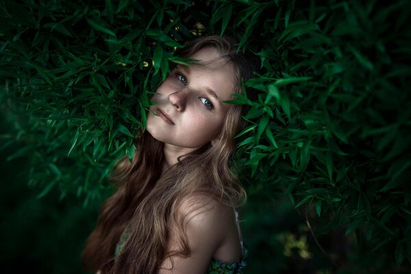 Długowłosa dziewczyna z piegami w środku zieleni