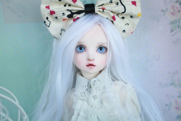 A doll with big eyes, a bow and white hair