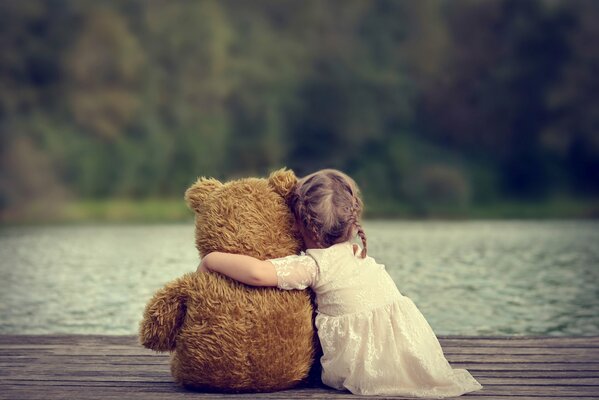 Fille sur fond de lac étreindre un ours en peluche