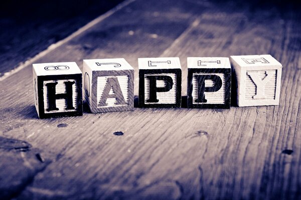 HAPPY inscription in cubes on a wooden surface