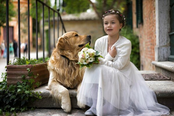 A girl in a white dress with a bouquet and a dog