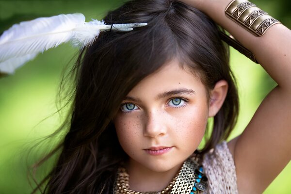 Petite fille avec les yeux verts et les cheveux noirs avec une plume