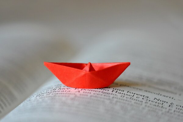 A red paper boat on a book page