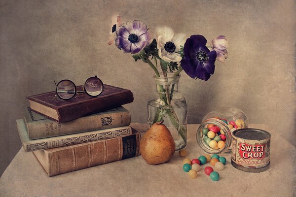On the table are books glasses a jar of dragee flowers