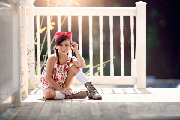 A girl in a red bandana on the summer veranda