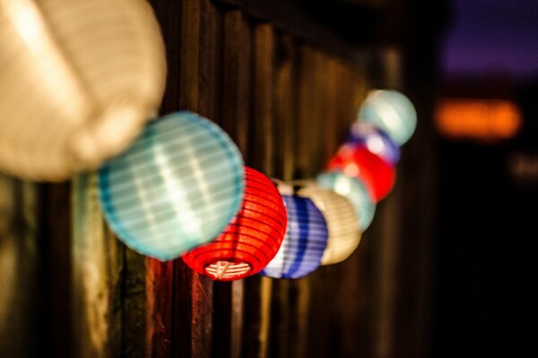 Multicolored lamps hanging on a wooden fence