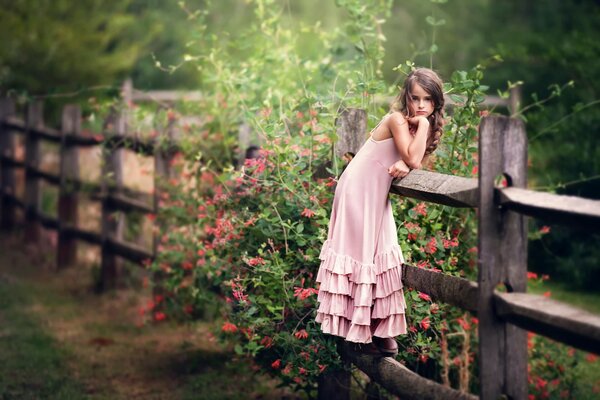 Chica en rosa en el fondo de una valla de madera