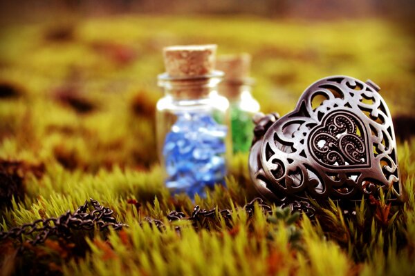 Der schmiedeeiserne Anhänger ist ein Herz auf einem Zapfhahn und kleine Flaschen mit magischem Inhalt. foto auf dem Rasen