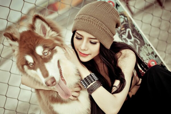 A girl in a hat with a husky dog