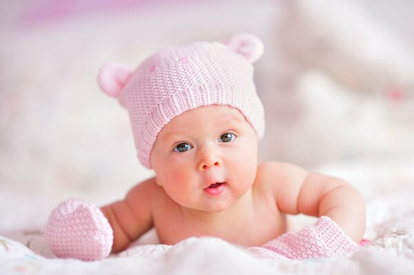 Lindo bebé recién nacido con gorro rosa y guantes