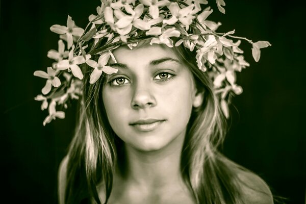 Cute girl in a wreath of delicate flowers