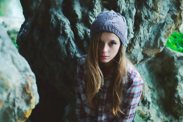 Chica con sombrero y camisa en el fondo de las rocas