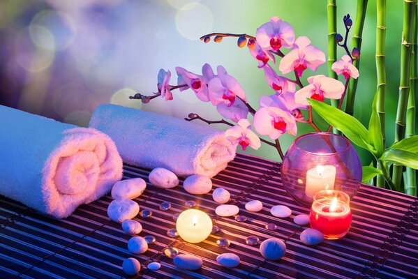 Spa atmosphere, heart-shaped stones are laid out on the surface, towels are rolled into a tube and candles are burning nearby