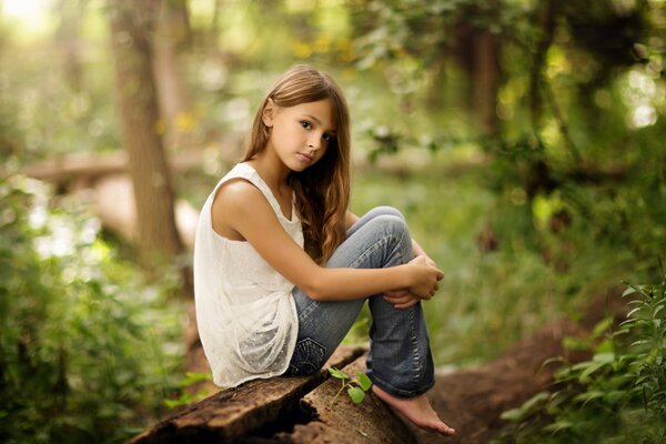Девочка сидит на природе обняв колени
