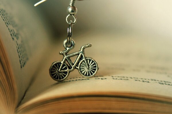 Bicycle keychain on the background of an open book