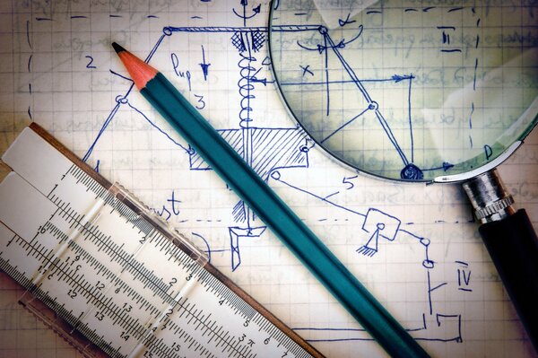 The slide rule, pencil and magnifying glass are on the notebook