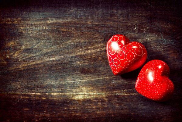 Two red hearts are lying on a wooden surface