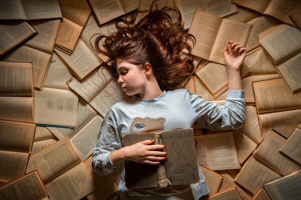 A girl in pajamas sleeps on books