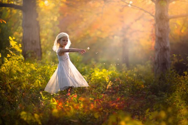 Fille en robe laisse un pissenlit dans le vent