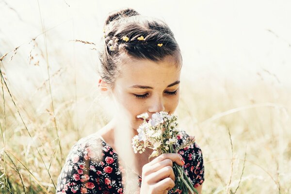 Jeune fille en été dans un champ reniflant un bouquet