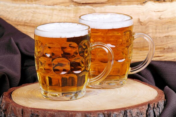 Mugs of beer on the stump. light beer with foam