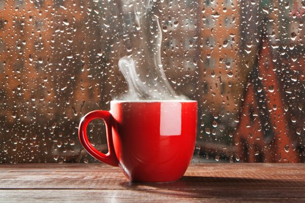 Tasse heißen Kaffee mit Rauch während des Regens