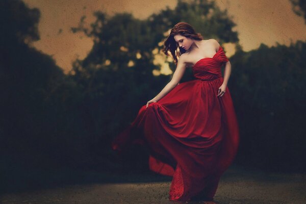 Chica en vestido rojo posando sobre un fondo oscuro