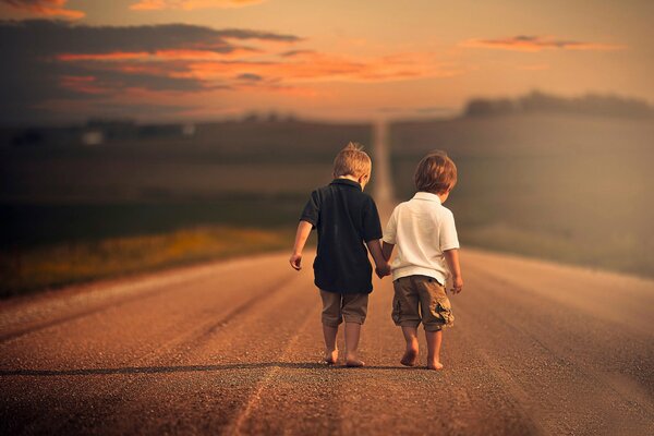 Dos niños caminan descalzos por un camino vacío