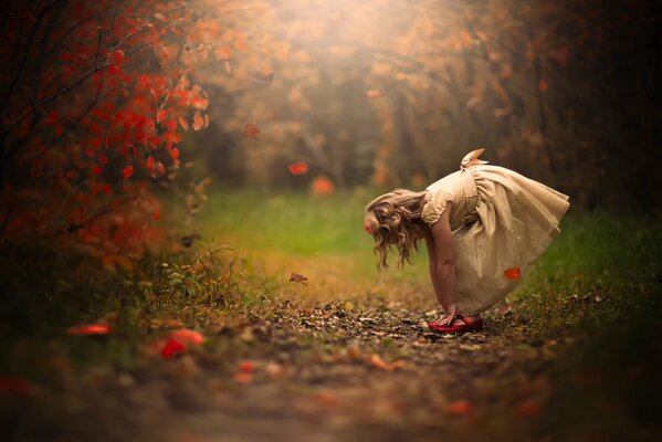 A girl in a dress in the middle of falling leaves